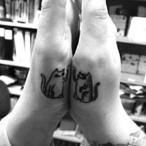 Zwei Handgelenke mit passenden Tattoo-Zeichnungen von Katzen, die sich zuwinken.