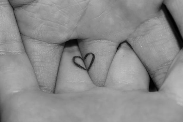 Ein kleines Herz-Tattoo zwischen zwei Fingern.