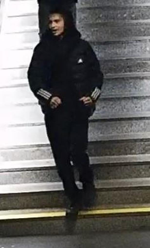 Eine Person in schwarzer Jacke und Hose steht auf einer Treppe.