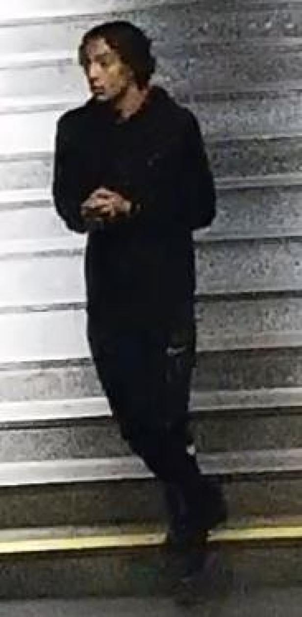 Ein junger Mann in dunkler Kleidung steht auf einer Treppe.