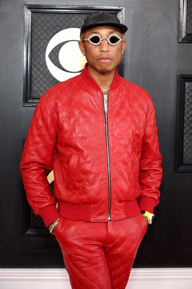 Pharrell Williams trägt eine rote Lederjacke und Hose mit Strasssteinen und eine Kappe.
