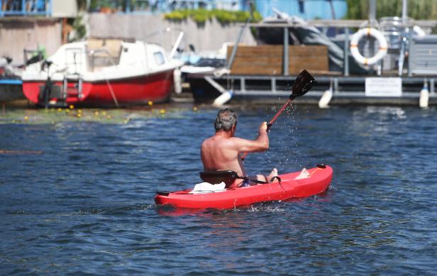 Ein Mann paddelt in einem roten Kajak auf dem Wasser.