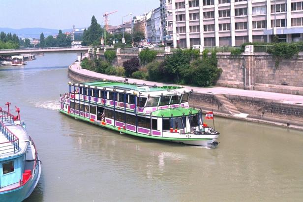 Ein Ausflugsschiff fährt auf einem Kanal in Wien.