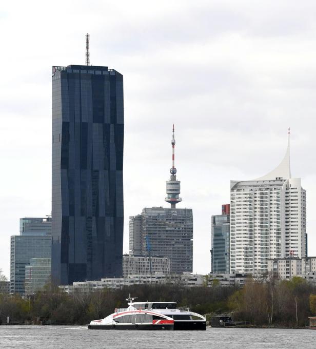 Blick auf die Skyline von Wien mit der Donau City und einem Ausflugsschiff im Vordergrund.