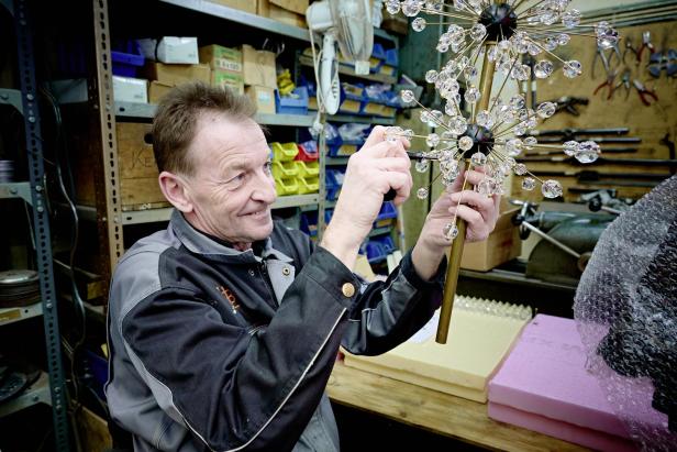 Ein Mann montiert eine dekorative Lampe mit Kristallverzierungen.