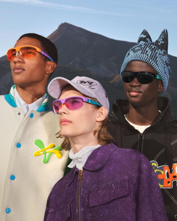 Drei Models präsentieren farbenfrohe Kleidung und Sonnenbrillen vor einer Bergkulisse.