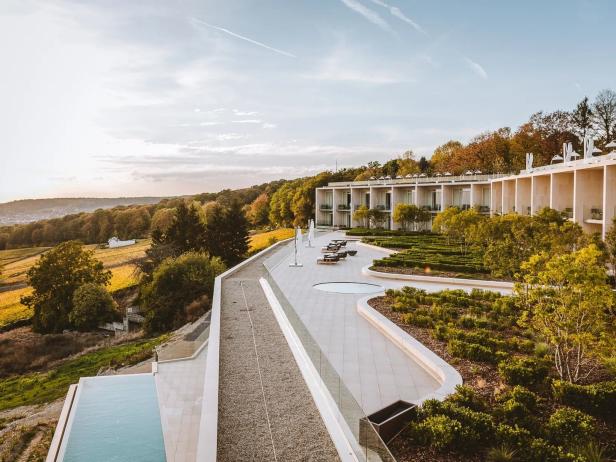 Ein modernes Hotel mit Pool und Blick auf die Weinberge im goldenen Abendlicht.