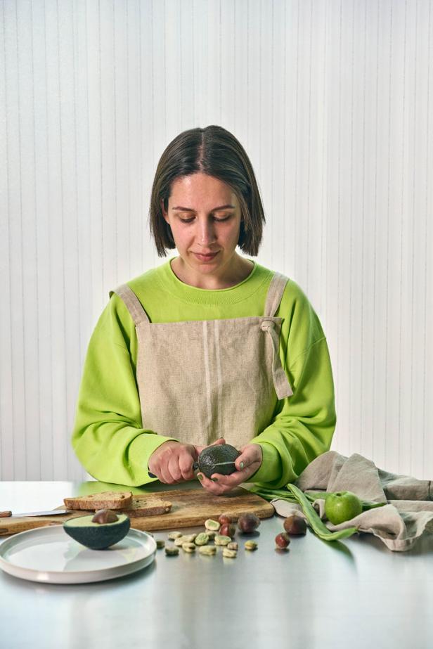 Eine Frau schält eine Avocado in einer Küche.