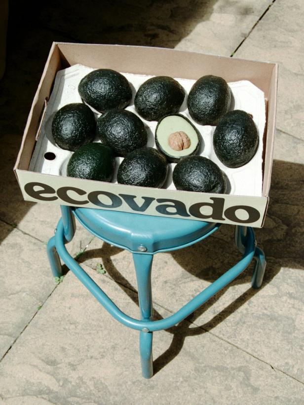 Eine Kiste mit Avocados steht auf einem blauen Hocker.