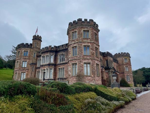 Ein großes Schloss mit mehreren Türmen unter einem bewölkten Himmel.