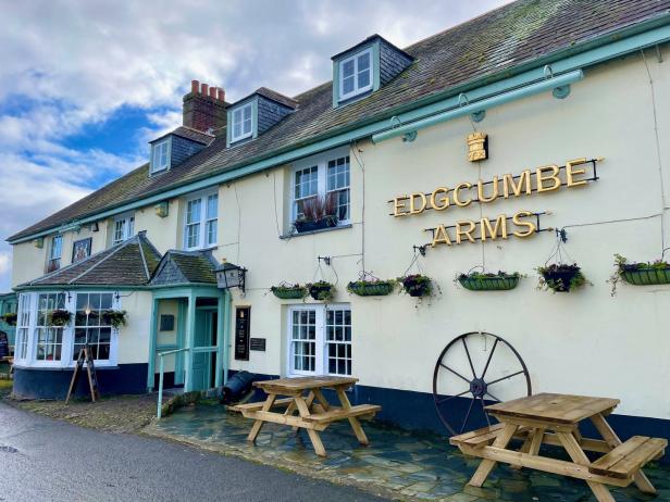 Das „Edgcumbe Arms“ Gasthaus mit Tischen im Freien an einem bewölkten Tag.