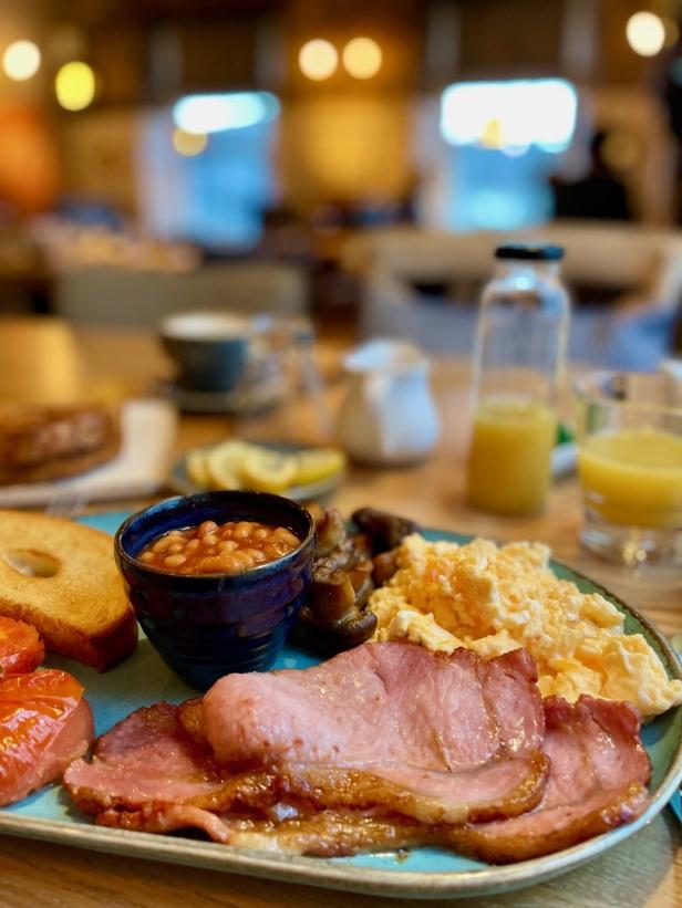 Ein Teller mit einem herzhaften Frühstück mit Speck, Rührei und Bohnen.