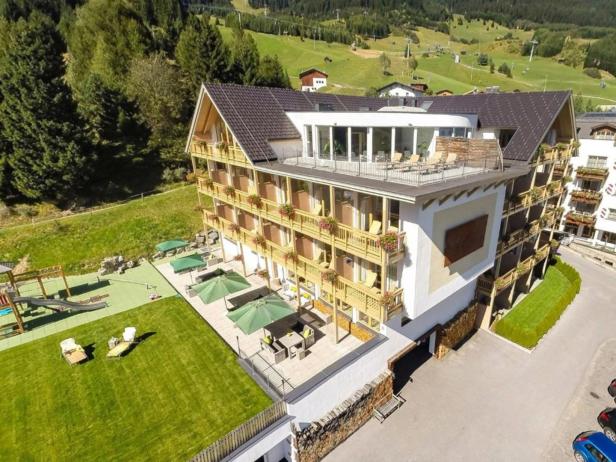 Ein mehrstöckiges Hotel mit Balkonen und einem Spielplatz im Grünen.