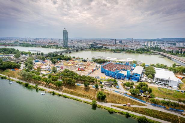 Luftaufnahme der Donauinsel in Wien mit der Skyline und einem Beachvolleyball-Turnier.
