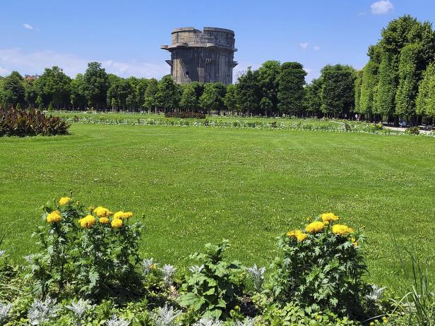 Ein Flakturm steht im Augarten in Wien, umgeben von Grünflächen und Bäumen.