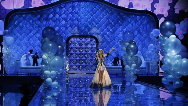 Taylor Swift tritt auf einer Bühne auf, die mit blauen Ballons und Lichtern dekoriert ist.