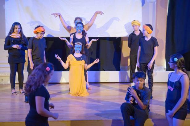 Eine Gruppe von Kindern führt ein Theaterstück auf einer Bühne auf.