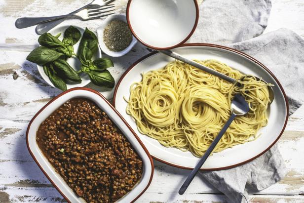 Spaghetti mit Linsen-Bolognese-Sauce auf einem Holztisch.