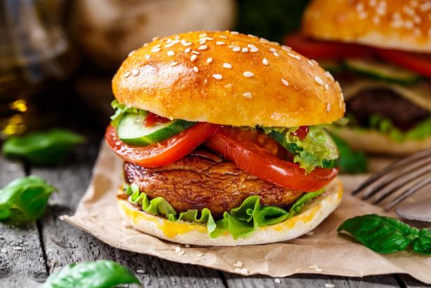 Ein vegetarischer Burger mit gegrilltem Gemüse liegt auf einem Tisch.