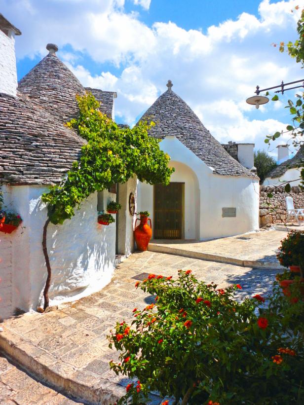 Ein Trullo mit einem kegelförmigen Dach und weiß getünchten Wänden in Apulien, Italien.