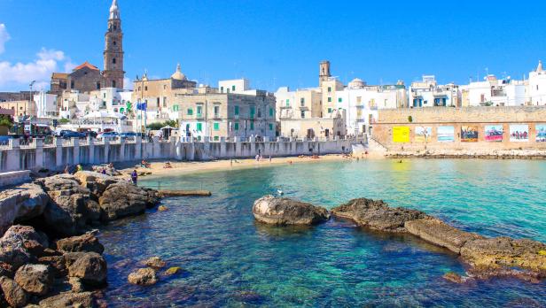 Die Küstenstadt Monopoli in Apulien mit einem kleinen Strand und klarem Wasser.