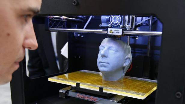 Ein Mann beobachtet, wie ein 3D-Drucker einen Kopf druckt.