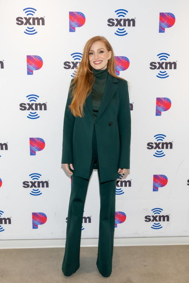 Jessica Chastain trägt einen grünen Hosenanzug vor einer SXM-Logowand.
