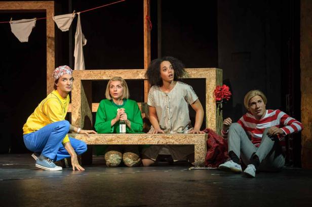 Vier Schauspieler auf einer Bühne vor einer Kulisse mit Wäscheleine.