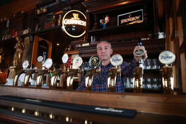 Ein Barkeeper steht hinter der Theke mit verschiedenen Biersorten vom Fass.