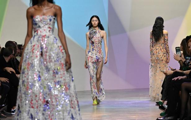 Models präsentieren farbenfrohe, bodenlange Kleider auf einem Laufsteg.
