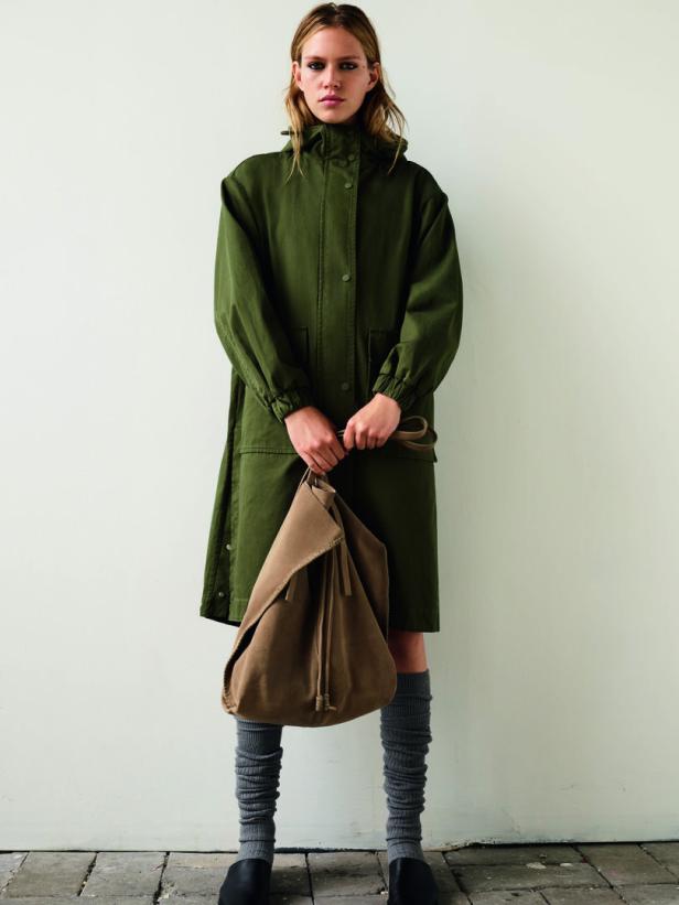 Eine Frau in einem grünen Parka hält eine braune Tasche.