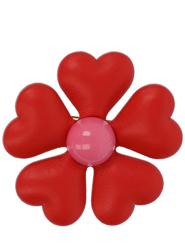 Eine rote Brosche in Form einer Blume mit herzförmigen Blütenblättern und einem rosa Mittelpunkt.