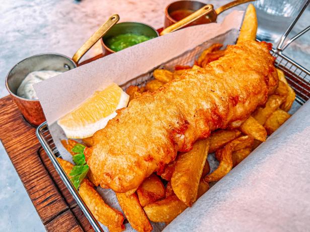 Ein Gericht mit Fish and Chips, serviert mit Zitrone und Dipsaucen.