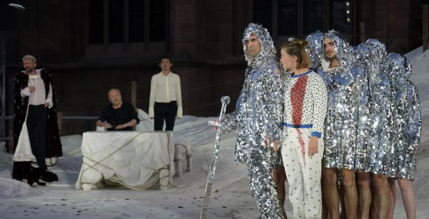 Eine Theaterszene mit Schauspielern in Kostümen, darunter Ritter in glitzernden Gewändern.