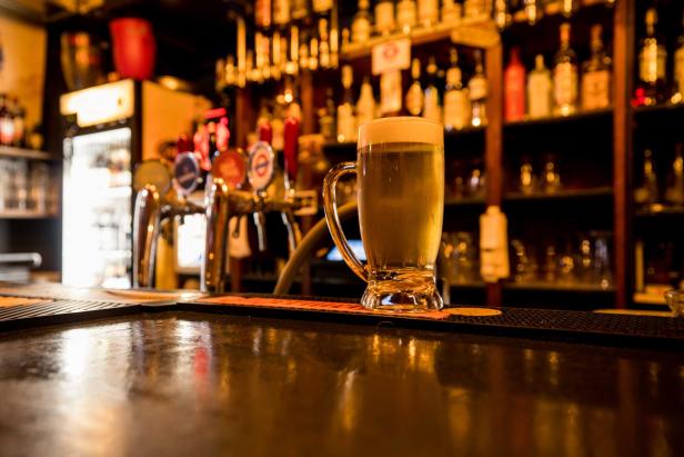 Ein Glas helles Bier steht auf einer Bar.