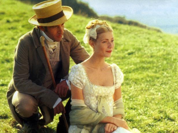 Gwyneth Paltrow und ein Mann in historischer Kleidung sitzen in „Emma“ auf einer Wiese.