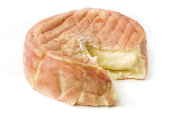Ein angeschnittener, runder Käse mit rötlicher Rinde und weichem Kern.