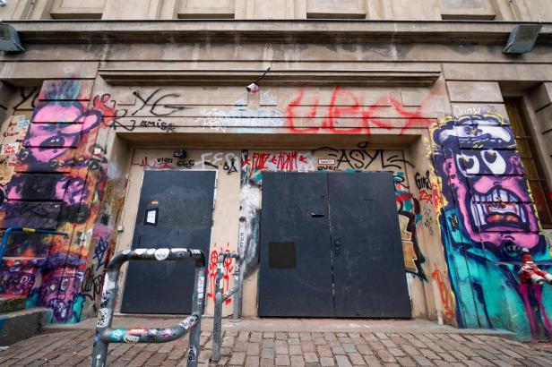 Zwei schwarze Türen in einem mit Graffiti bedeckten Gebäude.