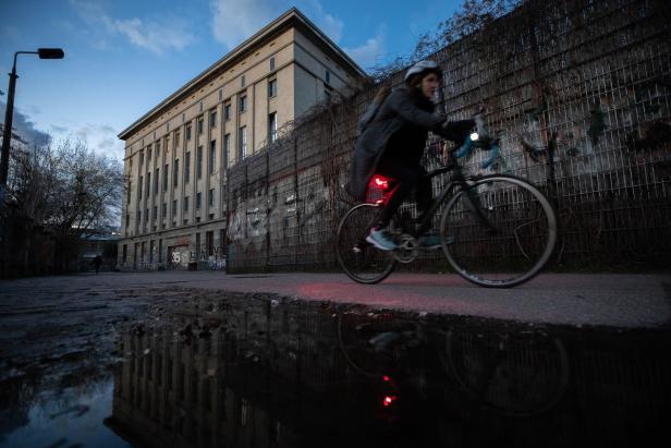 Eine Frau fährt mit dem Fahrrad vor dem Berghain in Berlin.
