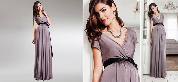 Eine Frau präsentiert ein langes, graues Umstandskleid mit schwarzer Schärpe.