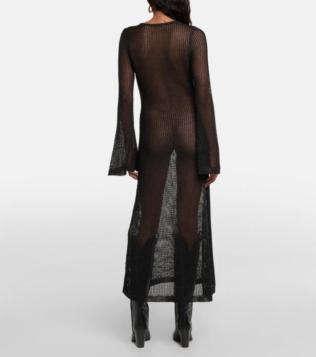 Eine Frau trägt ein transparentes, schwarzes Strickkleid und schwarze Stiefel.