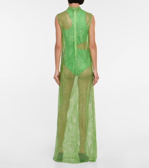 Eine Frau trägt ein grünes, transparentes Paillettenkleid über einem Badeanzug.