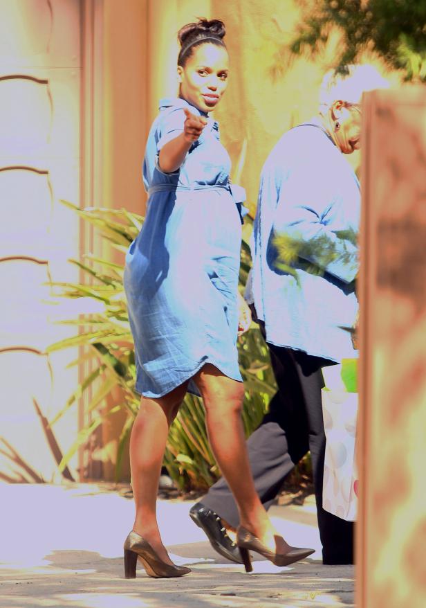 Kerry Washington geht in einem blauen Kleid und goldenen Schuhen die Straße entlang und zeigt mit dem Finger.