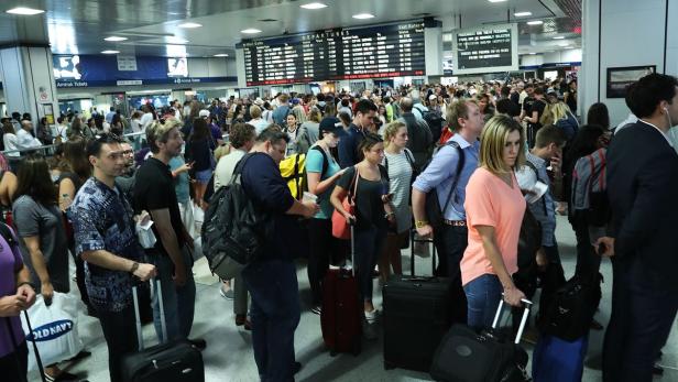 Eine große Menschenmenge wartet in einer Bahnhofshalle mit Anzeigetafeln.