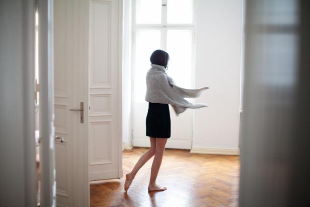 Barfuß tanzt eine Frau mit einem Tuch in einem hellen Raum.