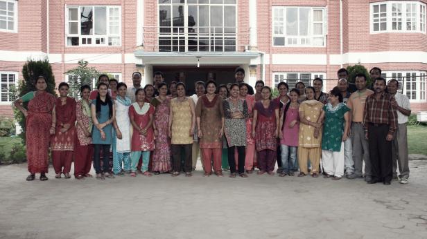 Eine Gruppe von Männern und Frauen steht vor einem Gebäude.