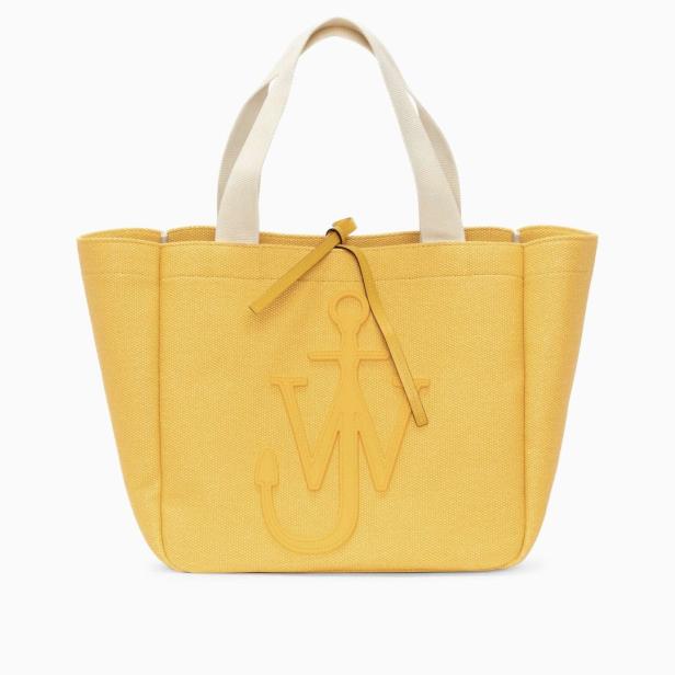 Eine gelbe J.W. Anderson Shopper-Tasche mit weißen Henkeln vor einem weißen Hintergrund.