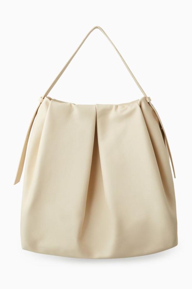 Eine geraffte, cremefarbene Handtasche mit einem einzelnen Trageriemen.