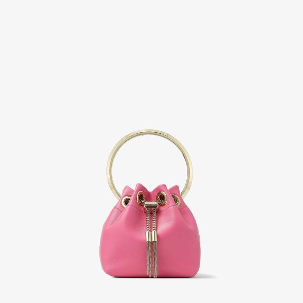 Eine kleine, pinkfarbene Handtasche mit goldenem Henkel und goldenen Quasten.