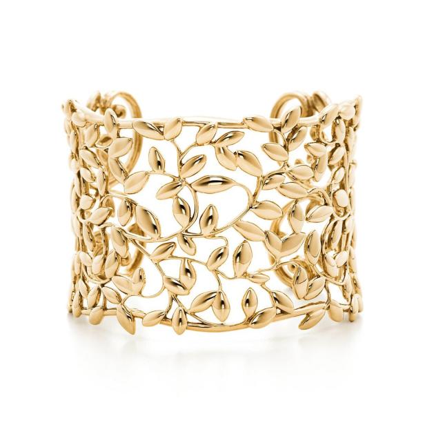 Ein goldenes Armband mit einem filigranen Blätterdesign auf einem weißen Hintergrund.